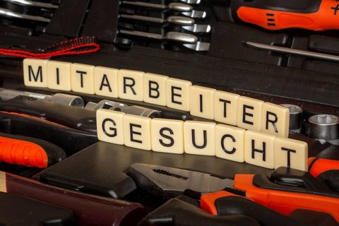 Symbol image employee search: In a toolbox, the words Employee wanted are written with letter cubes