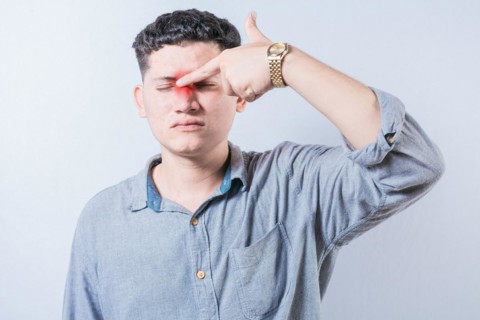 Man with nasal bridge pain isolated. Person with pain touching nose. Guy suffering with nasal