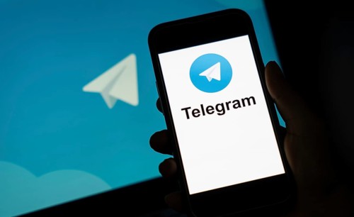 The social media Telegram messenger logo is being displayed on a smartphone screen and on a