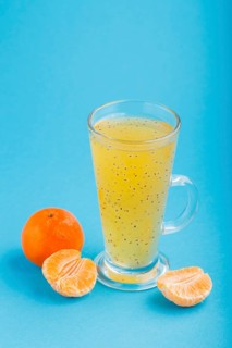 Glass of tangerine orange colored drink with basil seeds on a blue background. Morninig, spring,