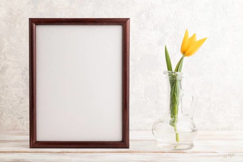Wooden frame with orange tulip flower in glass on gray concrete background. side view, copy space,