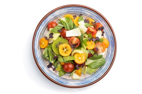Vegetarian salad of pac choi cabbage, kiwi, tomatoes, kumquat, microgreen sprouts isolated on white