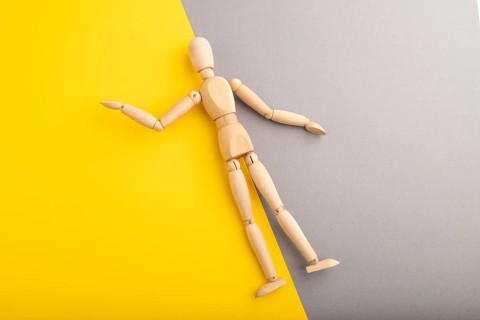 Wooden mannequin lies on gray and yellow pastel background. copy space, isolated, presentation