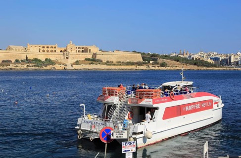 Mapfre Topcat ferry boat crossing harbour from Valletta to Sliema, Malta passing Fort Manoel