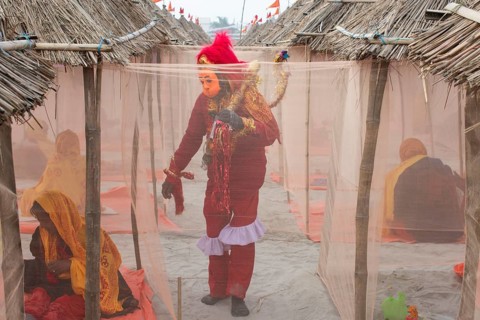 A devotee dressed as Hindu monkey-faced God Hanuman, standing next to camps, on the eve of