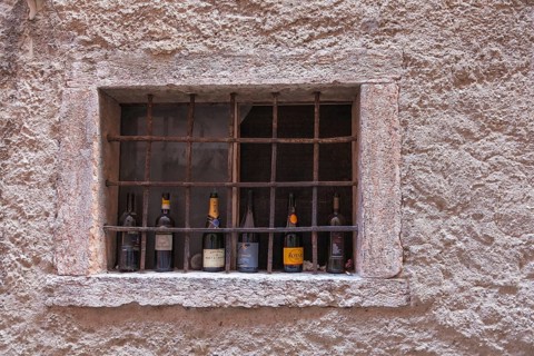Barred window with empty champagne and wine bottles, Malcesine, Lake Garda, Province of Verona,
