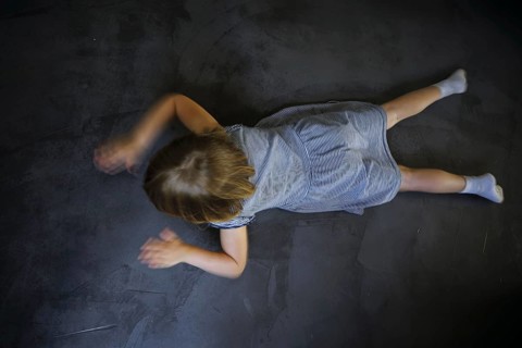 Symbol photo on the subject of tantrums (posed scene) . A little girl is lying on the floor,