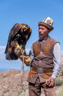 Traditional Kyrgyz eagle hunter with eagle in the mountains, near Kysyl-Suu, Kyrgyzstan, Asia