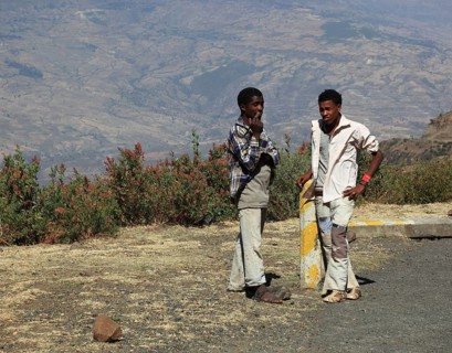 Landscape in the Choke Mountains, two young people waiting for the bus by the road, Ethiopia,