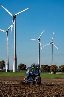 Farmer working in the fields, with a tractor, wind farm above the village of Lichtenau,