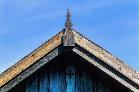 Roof ridge on an old wooden house with joinery and a cross on the gable