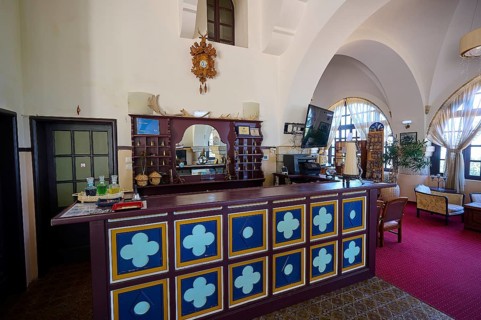 Elegant hotel reception with decorative counter, red carpets and arched windows, Elafos Hotel,