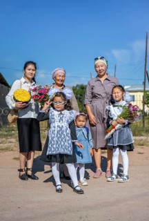 Family and schoolgirl with a bouquet of flowers on the first day of school, Issyk-Kul region,