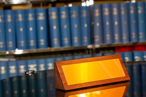 Brass sign with space for text in front of a large bookshelf