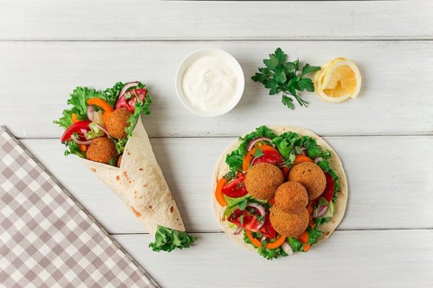 Tortillas, wrapped falafel balls, with fresh vegetables, vegetarian healthy food, on a wooden white
