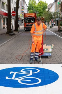 Application of road markings for a cycle lane, Rüttenscheider Straße in Essen, in the shopping and