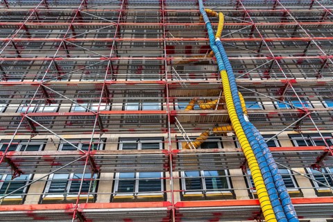 Large construction site, scaffolded shell of an office building complex, air hoses for building