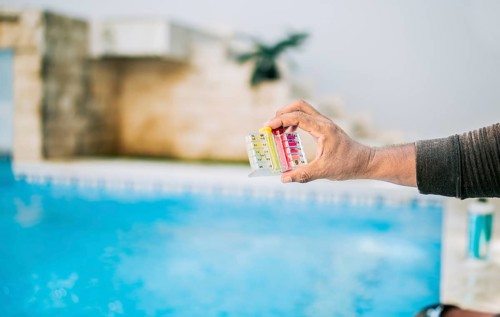 Hand showing tester kit to measure chlorine and ph in swimming pools. Person testing the PH of the