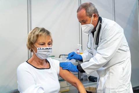 Vaccinator administers a vaccination, during the test run in the vaccination centre for corona
