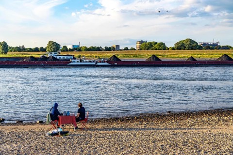 The Rhine at Duisburg-Baerl, man and woman having a picnic on the Rhine beach, at low tide, on the