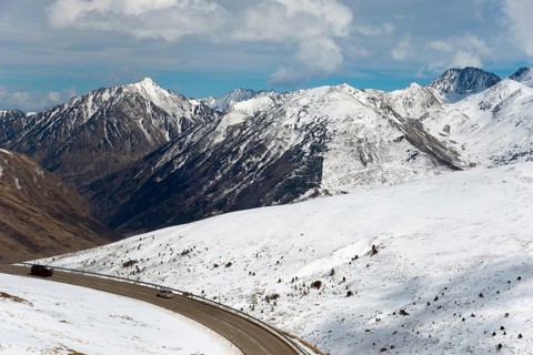 Verschneite Berge und eine kurvenreiche Straße in einer winterlichen Landschaft in Andorra,