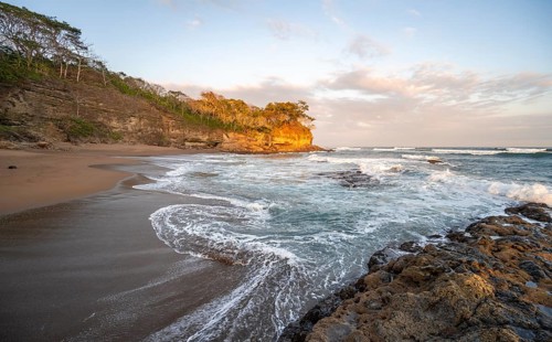 Sandy beach beach with rocks and sea at sunset, Playa Cocalito, coastal landscape, Pacific coast,