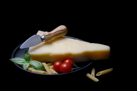 A piece of Parmesan cheese with cheese knife, pasta and tomatoes, Italy, Europe