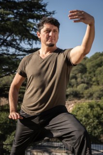 Vertical portrait from a low angle of a middle-aged Caucasian man training alone in martial arts.