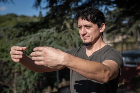 A Caucasian man adopts the Tree Hugging Posture during his Qi Gong training session. Rooted in