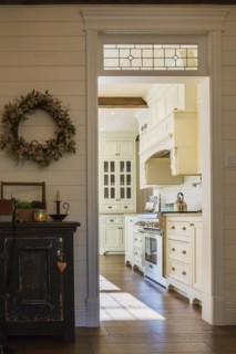 White painted maple wood antique style cabinets with tan coloured quartz countertops in kitchen