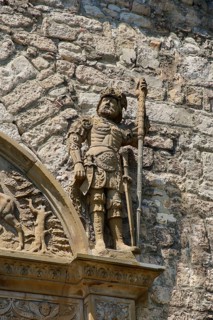 Stone figures, statue, male warrior above portal, detail, armour, weapons, decoration,