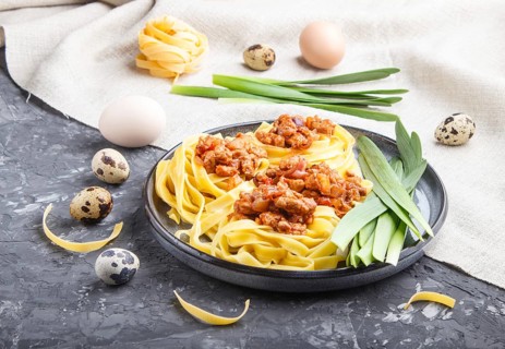 Tagliatelle bolognese pasta with minced meat on a black concrete background. side view, close up