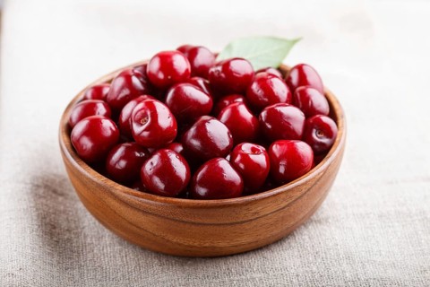 Fresh red sweet cherry in wooden bowl on wooden background. side view, close up