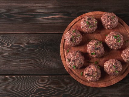 Raw meatballs, with micro greenery, on a cutting board, homemade, rustic, no people