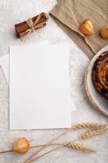 White paper invitation card, mockup with ear of wheat, bun, cup of coffee, linen textile, physalis
