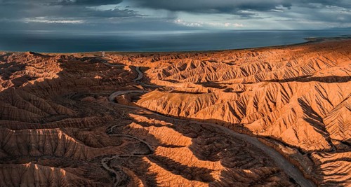 Riverbed runs through a landscape of eroded hills, badlands at sunset, Issyk Kul Lake in the