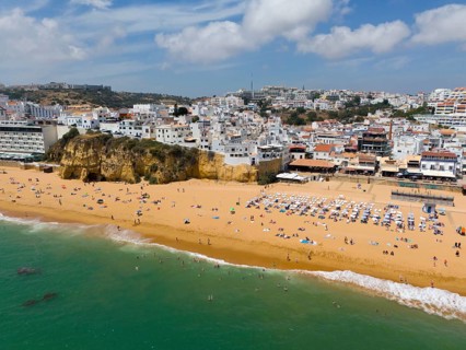 Coastal town with sandy beach, many bathers and buildings along the coast, aerial view, Albufeira,