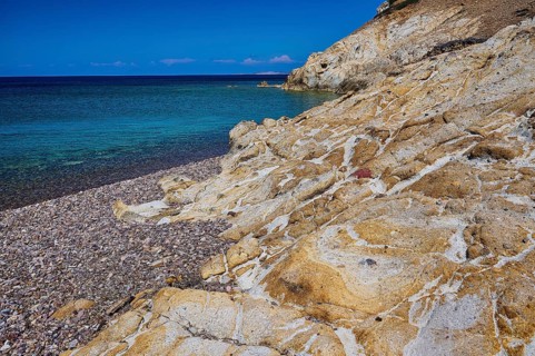Coastal scene with rocks and blue water under a clear sky, Lambi beach, pebble beach, Patmos,