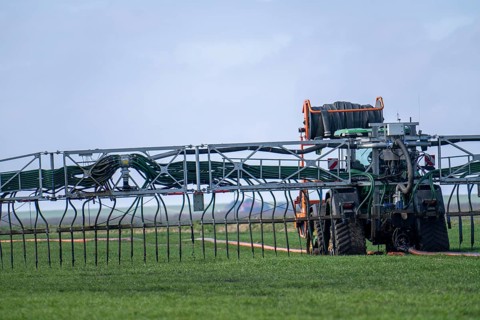 Tractor with boom for spreading liquid manure, on a field, fertilisation