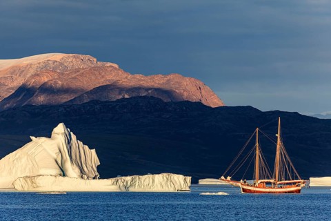 Sailing boat, ship in fjord in front of large icebergs and mountains, evening light, Scoresby
