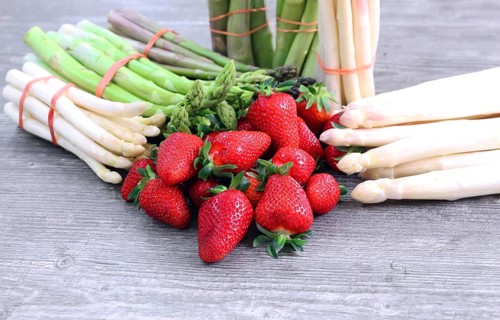 Green asparagus, white asparagus and fresh strawberries decorated on a rustic wooden table