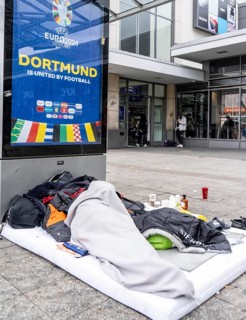 Homeless man sleeping in front of the entrance to Dortmund Central Station, North Rhine-Westphalia,