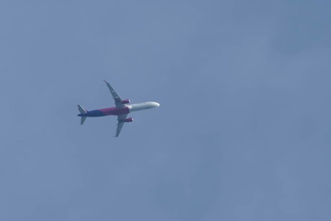 Airbus A320 aircraft of Wizz air airlines in flight across a blue sky, England, United Kingdom,