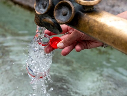 Water fountain, a woman fills drinking water into a small plastic bottle, Munich, Bavaria, Germany,