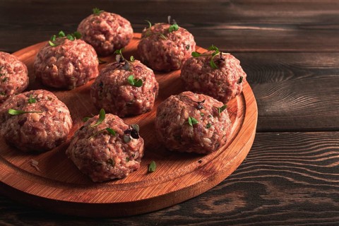 Raw meatballs, with micro greenery, on a cutting board, homemade, rustic, no people