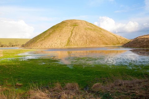 Silbury Hill ancient neolithic manmade chalk mound in Avebury, Wiltshire, England with flood water