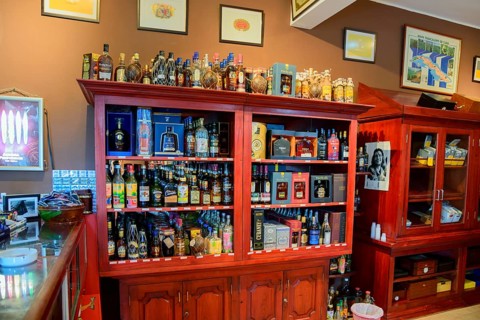 Inviting interior view of a bar with a selection of alcohol bottles on red wooden shelves and