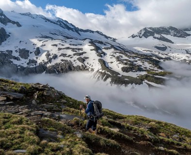 Mountaineers on a hiking trail, high fog in the valley, glaciated mountains with Furtschaglkees
