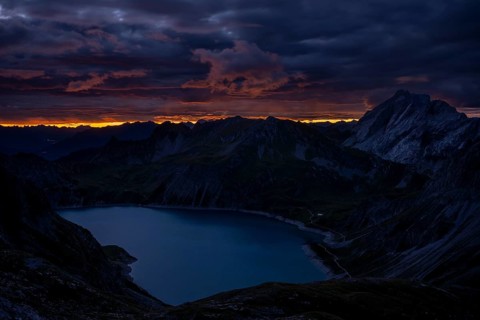Lake Lüner See with Montafon mountains and dramatic cloudy sky at sunrise, Tschagguns, Rätikon,