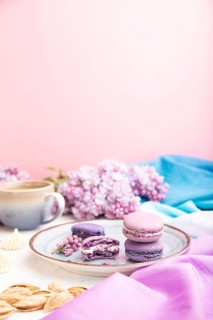 Purple macarons or macaroons cakes with cup of coffee on a white and pink background and